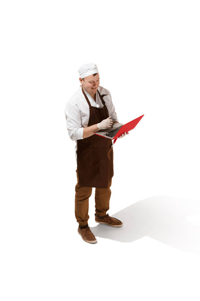 Serious butcher posing with a laptop isolated on white background - Fotoğraf, Görsel