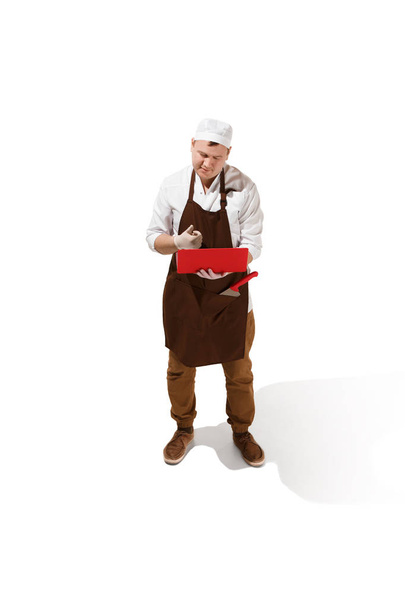 Serious butcher posing with a laptop isolated on white background - Fotó, kép