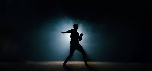 young man in casual clothers showing his dance on the dark street - Фото, изображение