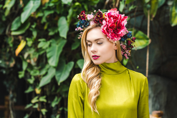 attractive young woman with floral wreath with green rainforest on background - Photo, Image