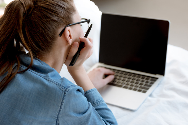 fiatal női teleworker használ laptop hálószobában hátulnézete - Fotó, kép
