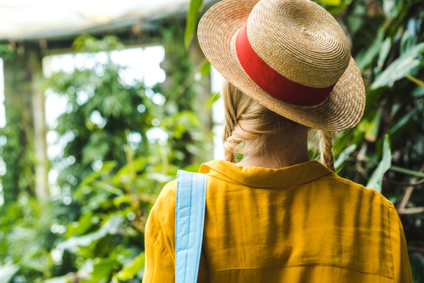 rear view of woman in straw hat surrounded with tropical plants - Fotoğraf, Görsel