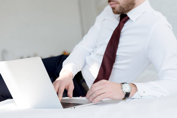 cropped view of businessman using laptop on bed - Photo, image
