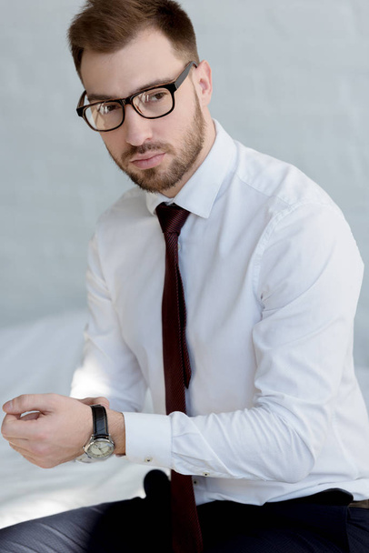 handsome businessman in watch posing near white wall - Foto, afbeelding
