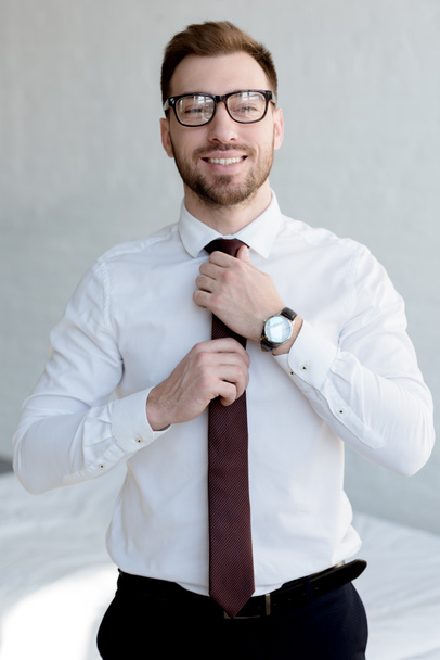 stylish businessman in tie posing near white wall - Foto, imagen