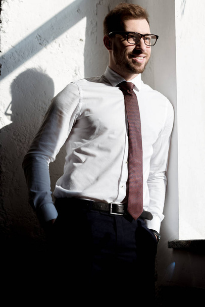 happy businessman in tie and glasses posing near white wall - Zdjęcie, obraz