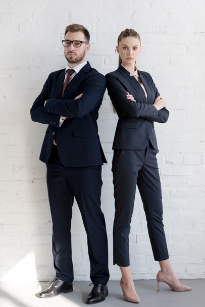 professional business team in suits posing with crossed arms near white wall - Фото, зображення