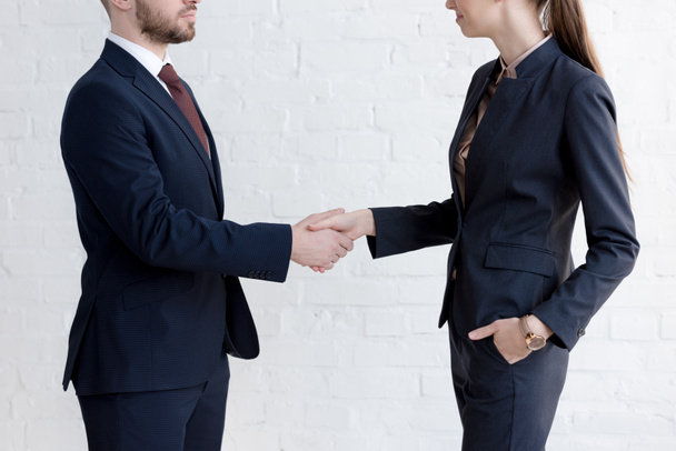 cropped view of businesspeople shaking hands near white wall - Foto, Imagem
