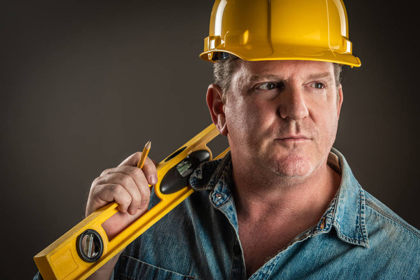 Serious Contractor in Hard Hat Holding Level and Pencil With Dramatic Lighting. - Photo, Image