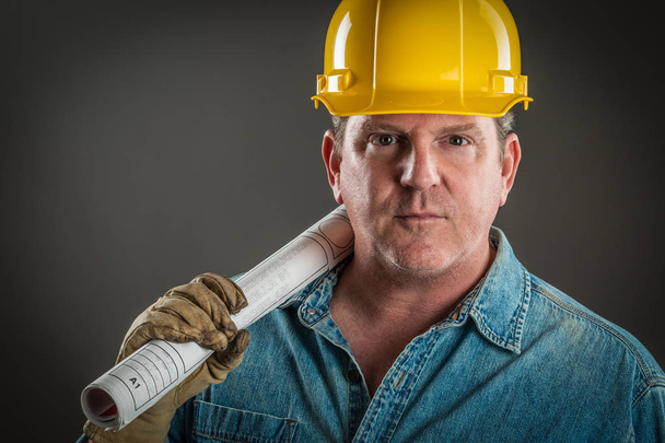 Serious Contractor in Hard Hat Holding Floor Plans With Dramatic Lighting. - Photo, Image