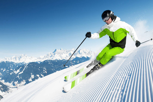 Skier in mountains, prepared piste and sunny day - Photo, Image