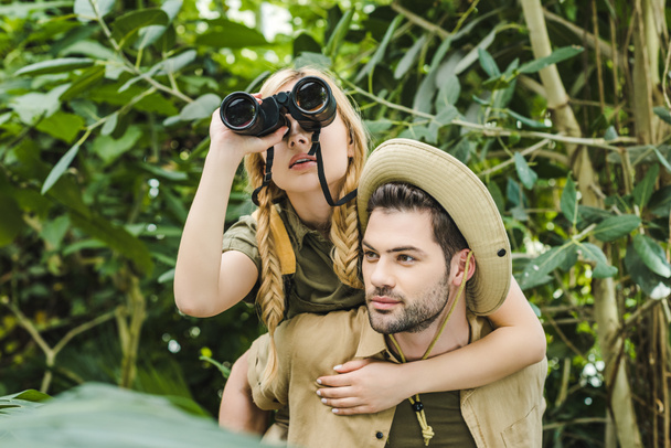 beautiful young couple in safari suits with binoculars hiking in jungle - Photo, Image
