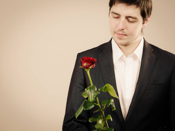 Elegant young man with red rose. - 写真・画像