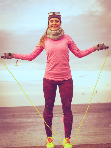 Woman training outdoor with jump rope on cold day - Foto, Imagen