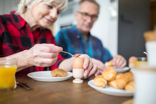 Senior woman breaking boiled egg for breakfast - Valokuva, kuva