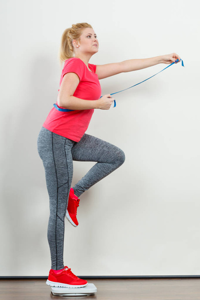 Woman wearing sportswear standing on weight machine - Foto, immagini