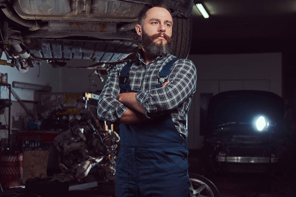 Két szakállas brutális mechanika javítás egy autó, a lift, a garázsban.  - Fotó, kép