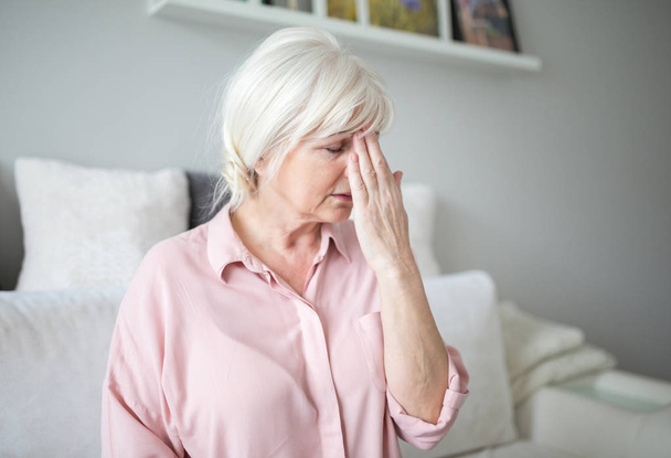 Senior lady with migraine touching her forehead - Foto, imagen