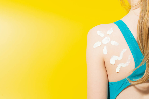 Adorable chica con traje de baño que ha aplicado crema protector solar en el hombro
 - Foto, Imagen
