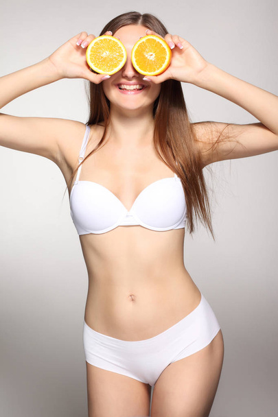 slender girl in white lingerie with orange - 写真・画像