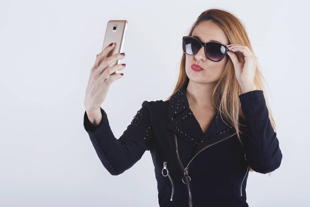 Mooie jonge vrouw nemen van een selfie op witte achtergrond - Foto, afbeelding