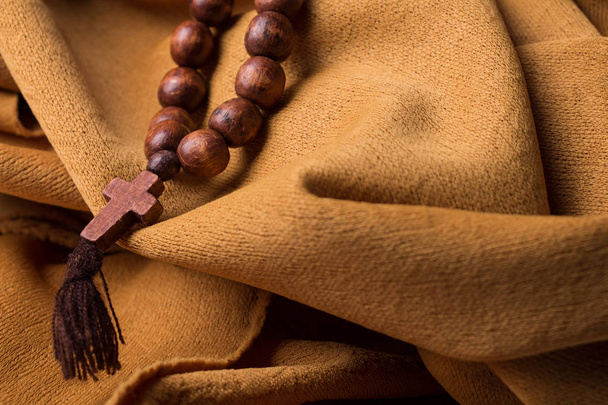 Дерев'яний християнський хрест і розарій на фоні золотої тканини драпірування
. - Фото, зображення