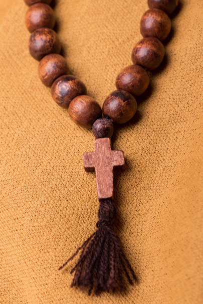 Деревянный христианский крест и четки на фоне золотой ткани драпировки
. - Фото, изображение