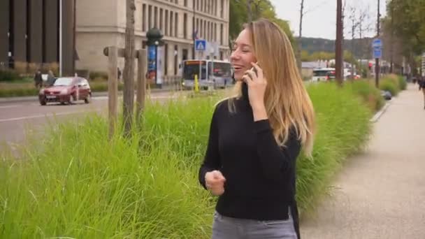 Velmi ženská osoba mluví o smartphone a chůzi u silnice. - Záběry, video