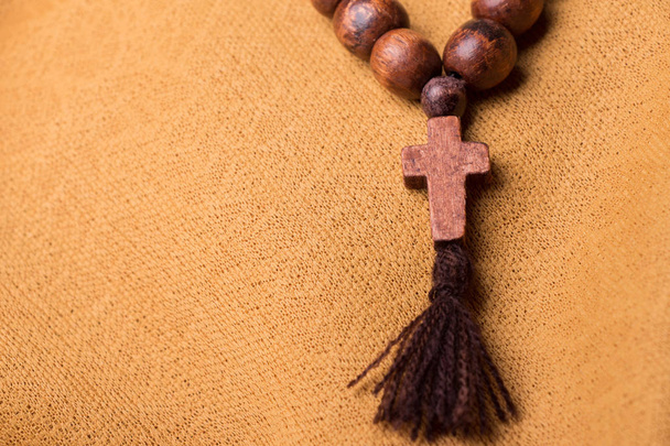Dřevěný křesťanský kříž a růženec na pozadí zlaté látky draperie. - Fotografie, Obrázek