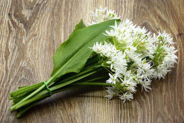 Bunch of ramson wild ail flower heads and leaves on wooden ta
 - Photo, image
