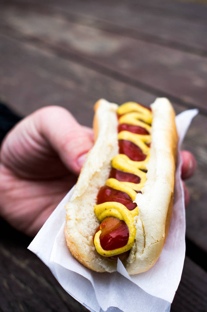 A mans hand holding  yumm hot dog - Foto, imagen
