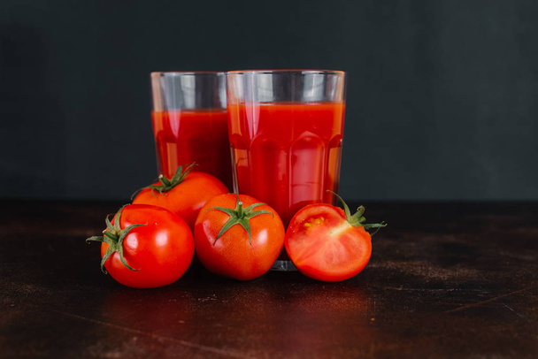 Suco de tomate fresco e tomates em uma mesa de madeira
 - Foto, Imagem