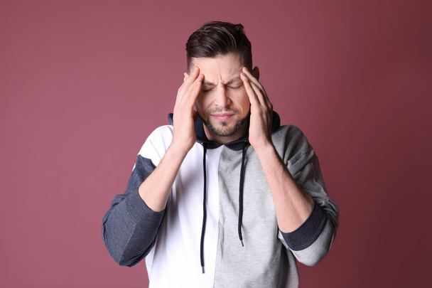 Man suffering from headache on color background - 写真・画像