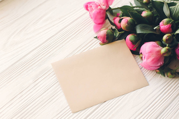 素朴な白い木製の背景の空のクラフト カードでロマンチックなピンクのシャクヤク ブーケ - 写真・画像