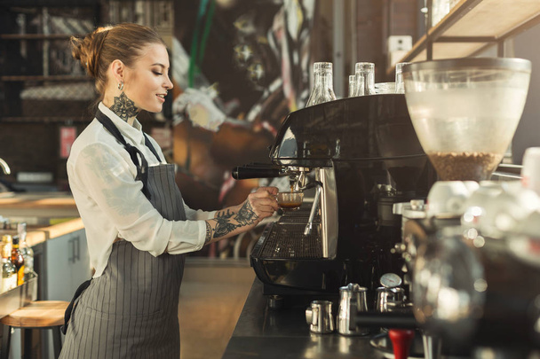 Tattooed barista making coffee in professional coffee machine - Photo, Image