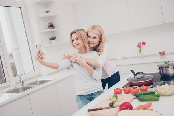 Mother and daughter having fun on the modern white kitchen while - Foto, immagini