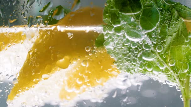 Μακροεντολή βίντεο 4k φυσαλίδες σε νεροπότηρο φρέσκο κρύα λεμονάδα με λεμόνια και δυόσμο - Πλάνα, βίντεο