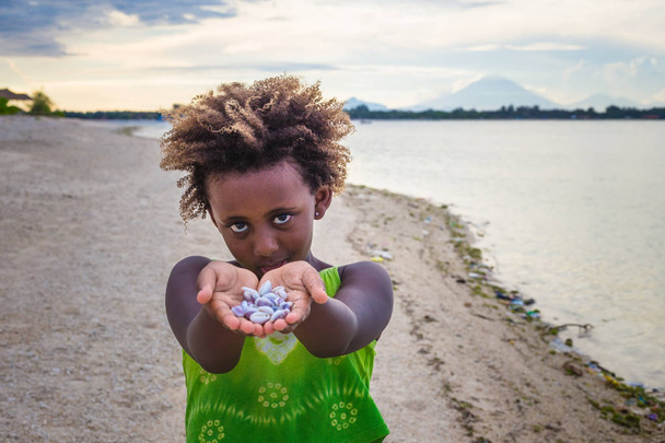 Meisje permanent op strand en het tonen van schelpen, Indonesië - Foto, afbeelding