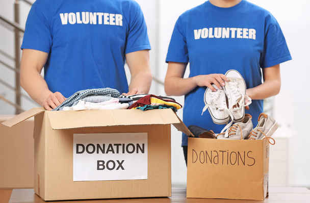 Volunteers putting clothes and shoes in donation boxes indoors - Fotó, kép