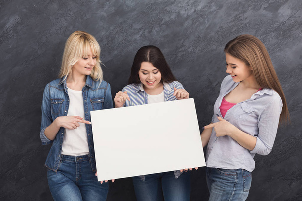Drie vriendinnen houden van lege witte spandoek - Foto, afbeelding