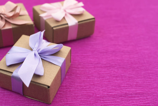 Святкова композиція три Крафт-коробки з подарунками на яскраво-рожевому тлі
. - Фото, зображення