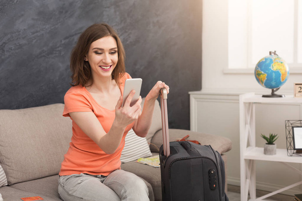 Woman ready for travel, sitting with suitcase - Photo, image