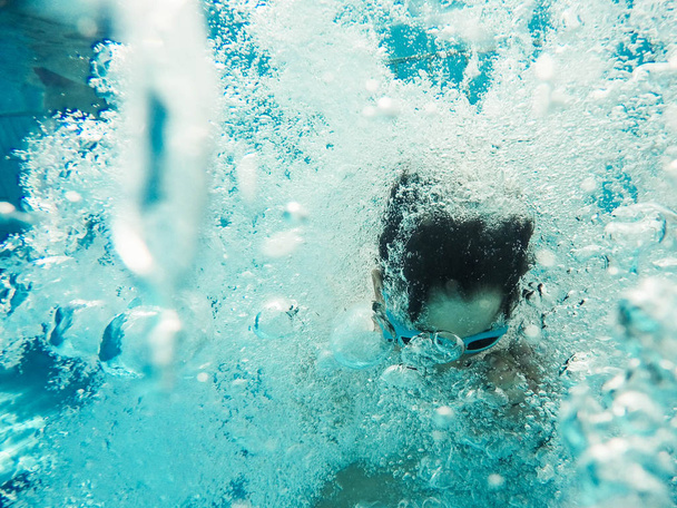 Подводный вид мальчика, прыгающего в бассейн
 - Фото, изображение