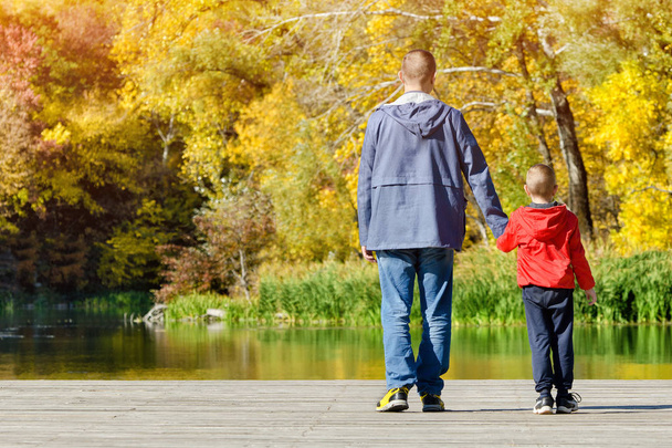 Father and son are walking along the pier. Autumn, sunny - 写真・画像