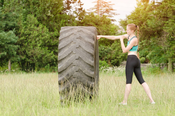 Young woman boxing with the tire. Workout - Fotó, kép