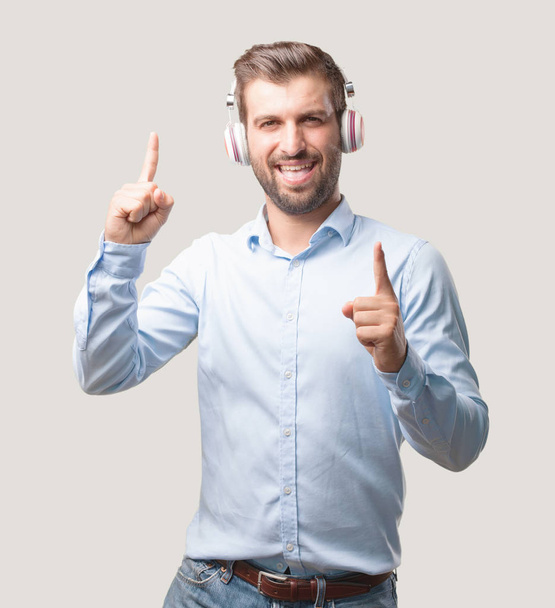 Young handsome man dancing with headphones wearing a blue t shirt. Person isolated against monochrome background. - Foto, Imagem