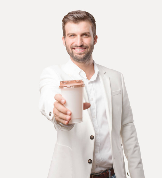 young handsome businessman with a take away coffee, white blazer, satisfied or happy expression. Person isolated against monochrome background. - Foto, Imagen