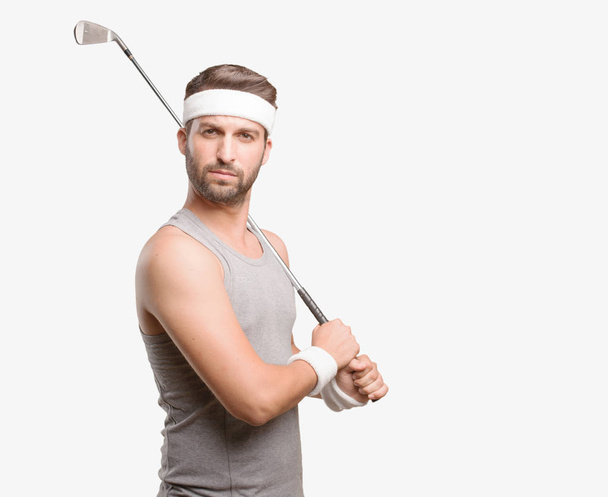 Young handsome sportsman with golf brat wearing gray tank top. Person isolated against monochrome background. - Foto, afbeelding