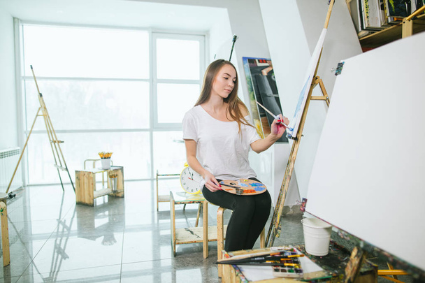 Time for creating. Attractive woman posing fullface while painting a sea-scape - Фото, изображение