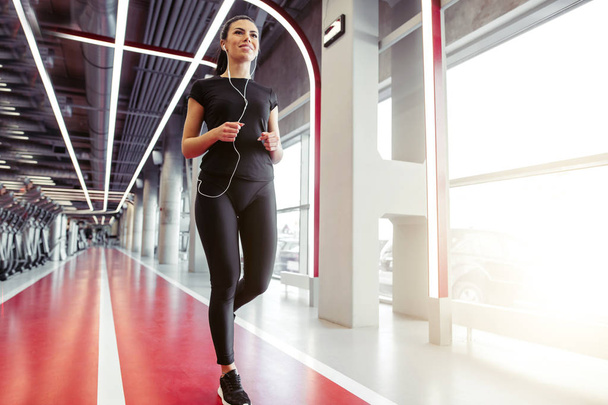 woman with earphones running on indoor track at gym - Φωτογραφία, εικόνα